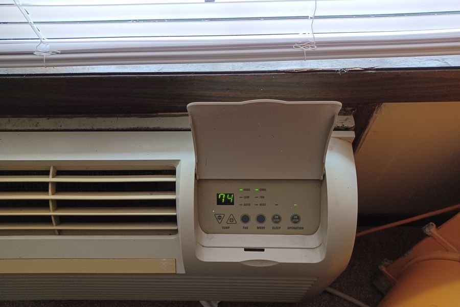 Through-wall packaged terminal air conditioner unit mounted below a window