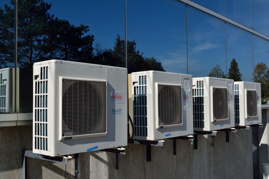 Row of wall-mounted ductless mini-split condenser units outside a building