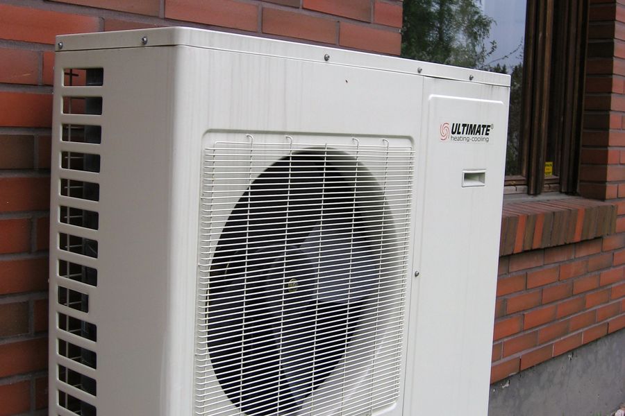 Outdoor air-conditioning condenser unit mounted beside a brick house